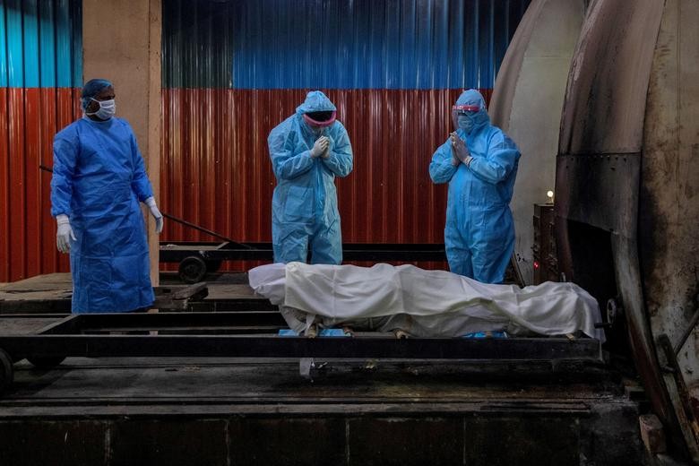 Relatives pray before the cremation of a woman, who died due to the coronavirus, at a crematorium in New Delhi, India. REUTERS/Danish Siddiqui